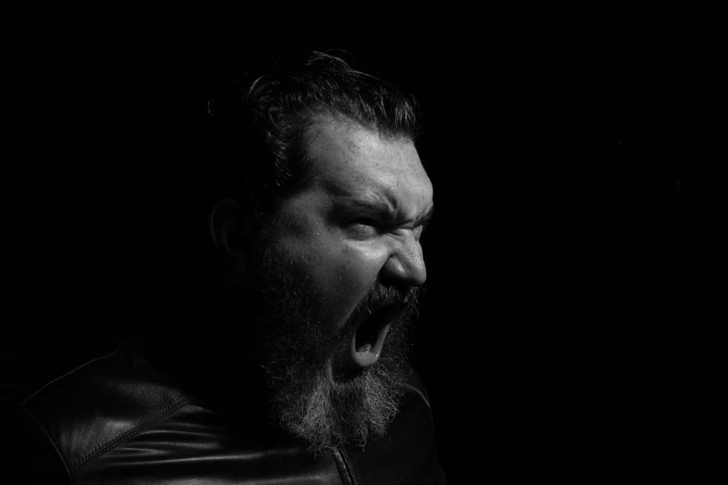 Bearded Mid Adult Man Screaming Against Black Background.