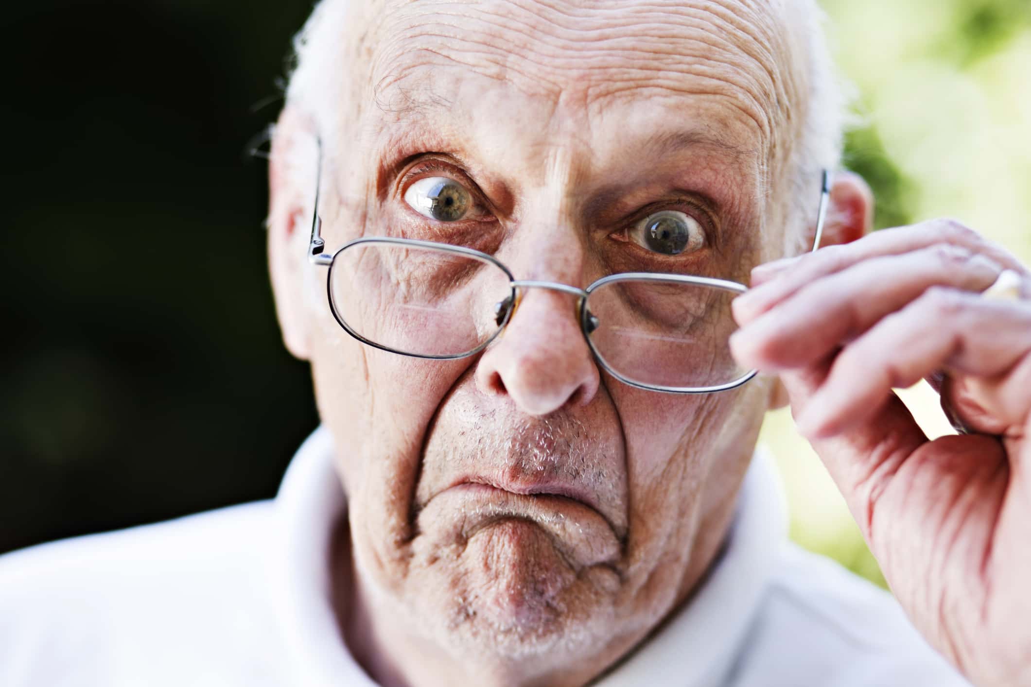 Grumpy old man looks over spectacles, shocked and disapproving.