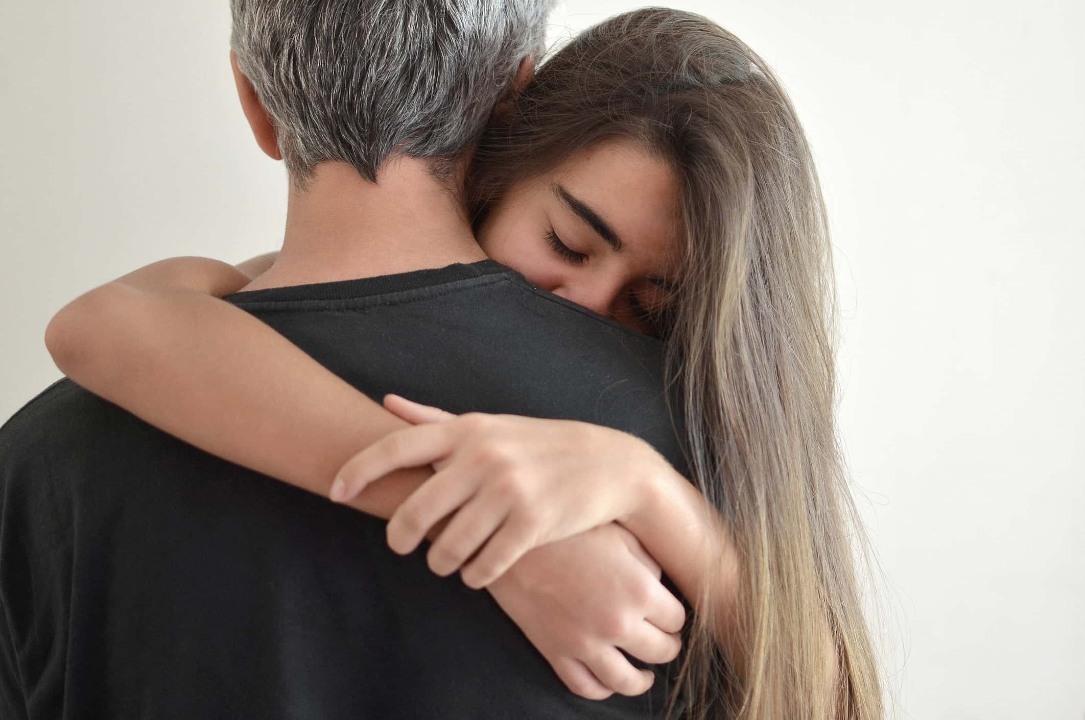 Teenage girl hugging her father.